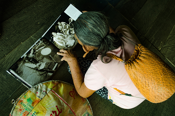 A woman studies photos in a book in Long Luyang, Tinjar. – Photos by C Horn and R Riman