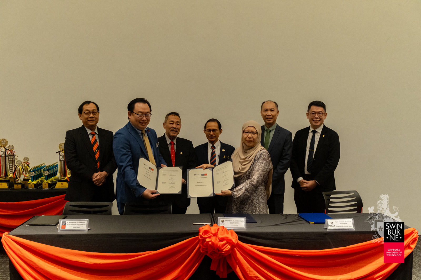 Ir Professor Lau Hieng Ho (second left) and Professor Dr Yatimah Alias (third right) hold up the signed MoU between Swinburne Sarawak and UM.