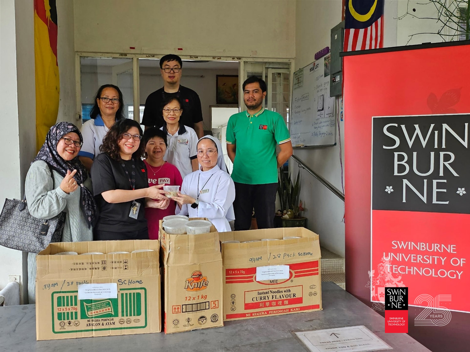 Ms Andrea Sim (front row, second left) hands over the bubur lambuk to a representative from the Sarawak Cheshire Home as Nurlida Mohamad Salleh (front row, left) and other Swinburne Sarawak Staff Recreational Club members look on.